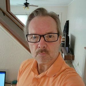 headshot of man with mustache wearing glasses